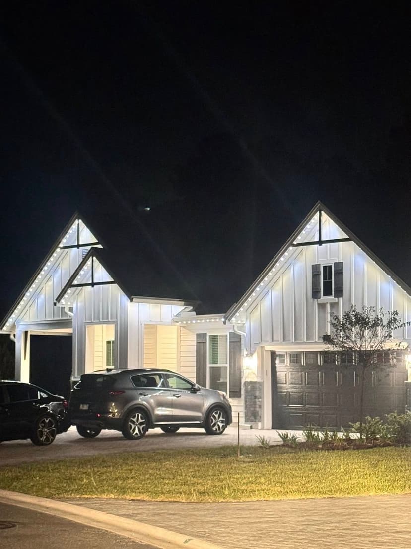 Modern house with illuminated exterior and landscaped front yard at night.